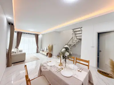 Elegant open-plan living and dining area with modern staircase and natural light.