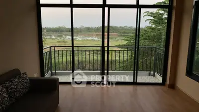 Spacious living room with large windows and balcony overlooking serene nature view.
