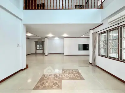 Spacious open-plan living area with tiled flooring and large windows.
