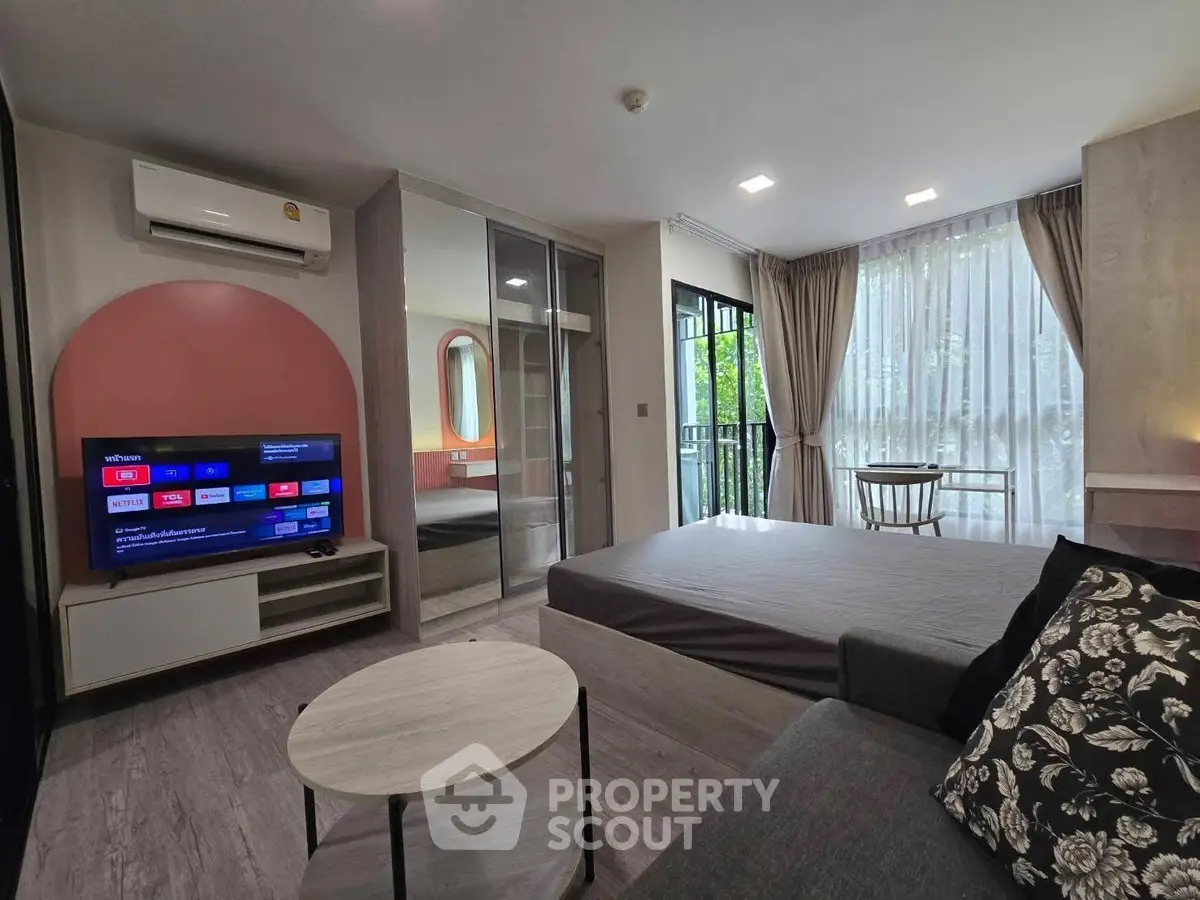 Modern studio apartment with stylish decor and natural light, featuring a cozy living area and balcony access.