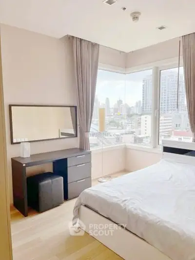 Bright and modern bedroom with city view, featuring large windows and stylish furniture.