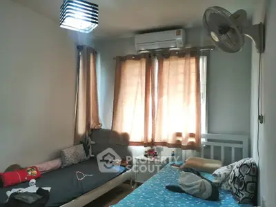Cozy bedroom with twin beds, air conditioning, and natural light from curtained windows.