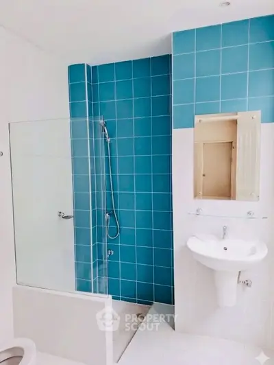 Modern bathroom with blue tile shower and sleek white fixtures