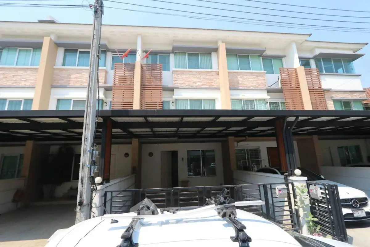 Modern townhouse exterior with carport and balcony, ideal urban living space.