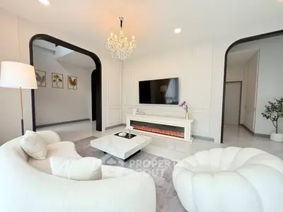 Luxurious modern living room with elegant chandelier and plush white furniture.