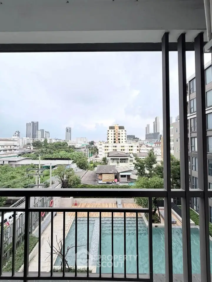 Stunning cityscape view from a modern balcony overlooking a pool and urban skyline.