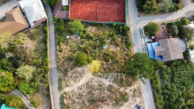 Aerial view of a residential area with tennis court and surrounding greenery.