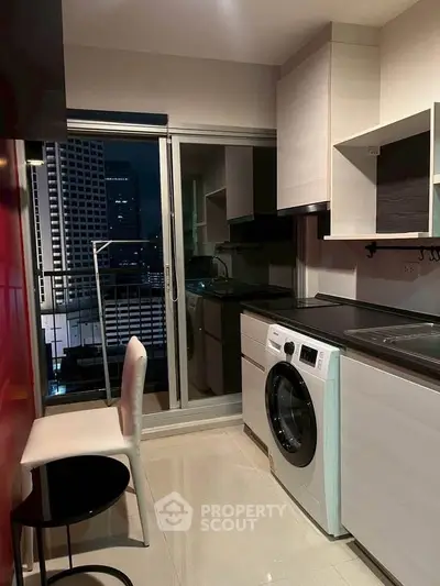 Modern kitchen with washing machine and city view from balcony at night.