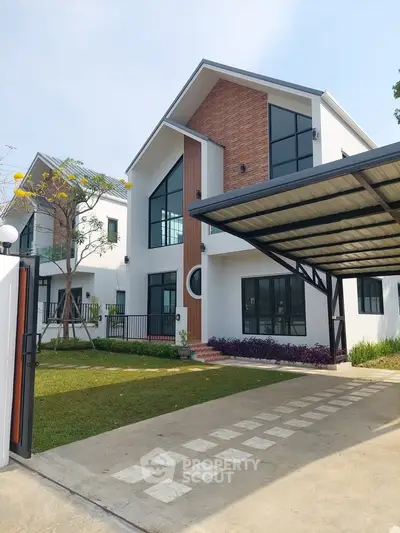 Modern two-story house with large windows and a carport, surrounded by a well-maintained garden.