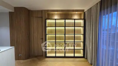 Elegant modern living room with illuminated wooden shelving and floor-to-ceiling curtains.