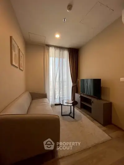 Cozy living room with modern decor, featuring a comfortable sofa, TV, and natural light from large window.