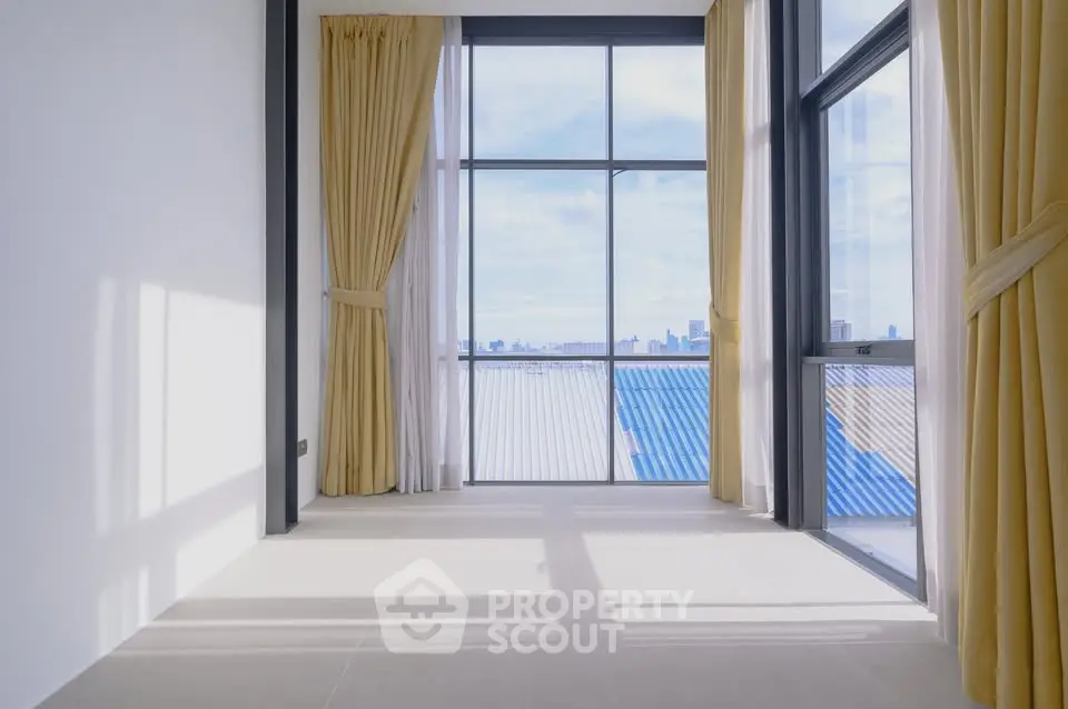 Spacious room with floor-to-ceiling windows offering stunning city views and abundant natural light.