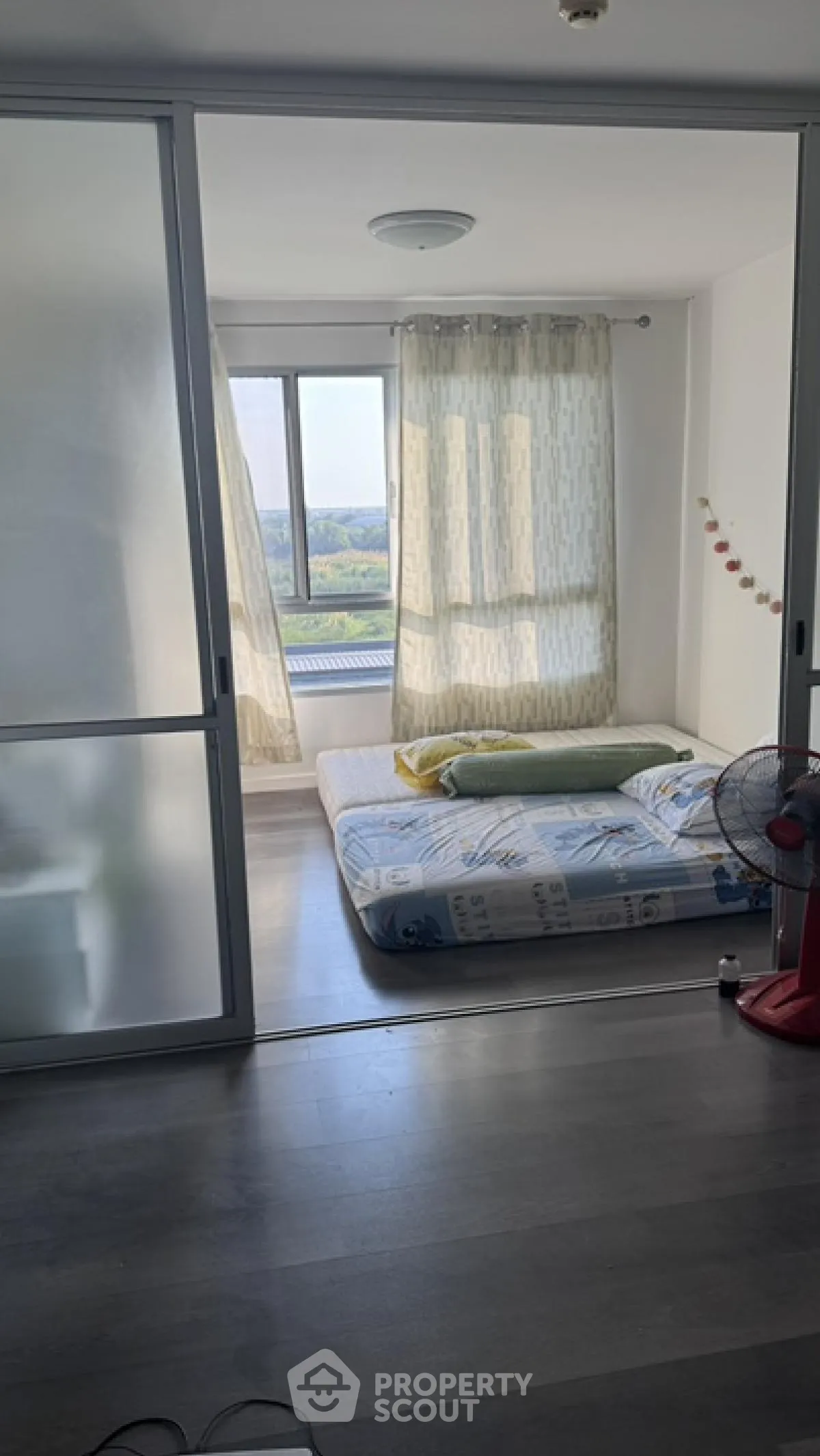 Cozy bedroom with large window offering scenic views, featuring minimalist decor and natural light.