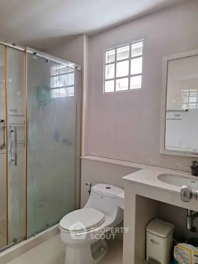 Modern bathroom with glass shower and sleek vanity in bright natural light.