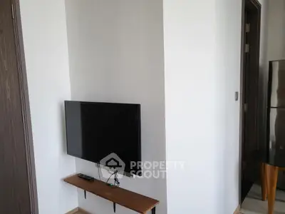 Modern interior with wall-mounted TV and sleek wooden shelf in a minimalist living space.