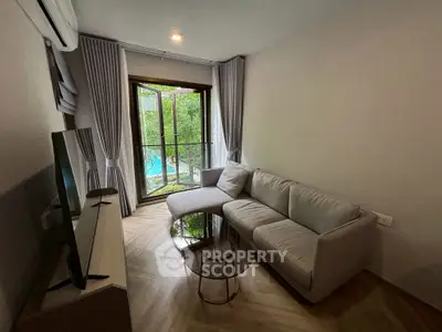 Cozy living room with modern sofa and glass coffee table, overlooking lush garden view.