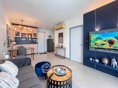 Modern living room with stylish decor, open kitchen layout, and wall-mounted TV in a cozy apartment.