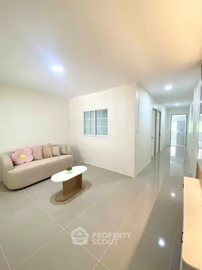 Spacious modern living room with sleek tile flooring and cozy sofa in a bright, minimalist apartment.