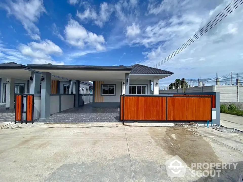 Modern single-story house with spacious driveway and stylish wooden gate