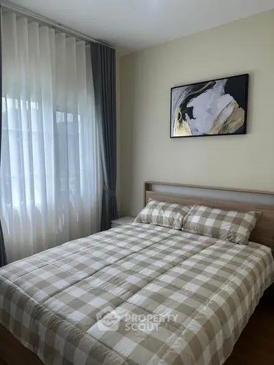Cozy bedroom with checkered bedding and modern art on the wall, perfect for relaxation.