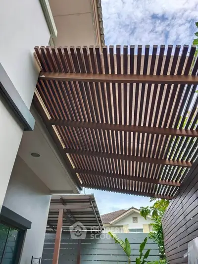Modern house exterior with stylish wooden pergola and lush greenery