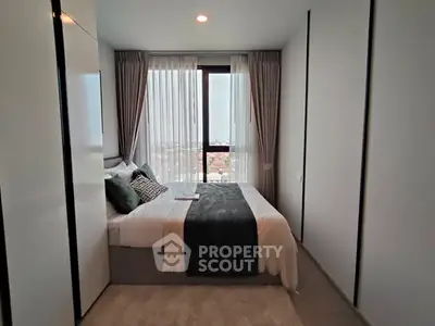 Modern bedroom with large window and stylish decor in high-rise apartment.