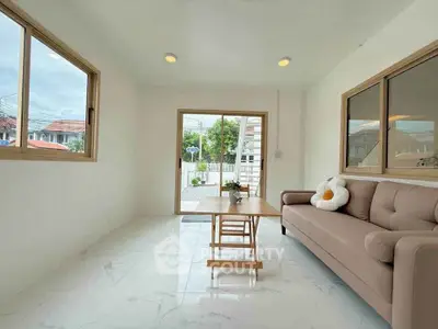 Bright living room with modern sofa and large windows offering natural light and garden view.