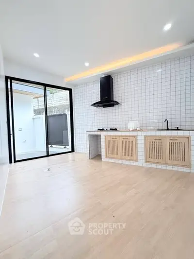 Modern kitchen with open layout and sleek design, featuring tiled backsplash and sliding glass doors.