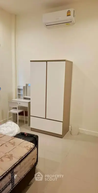Cozy bedroom with modern wardrobe and air conditioning unit, ideal for comfortable living.