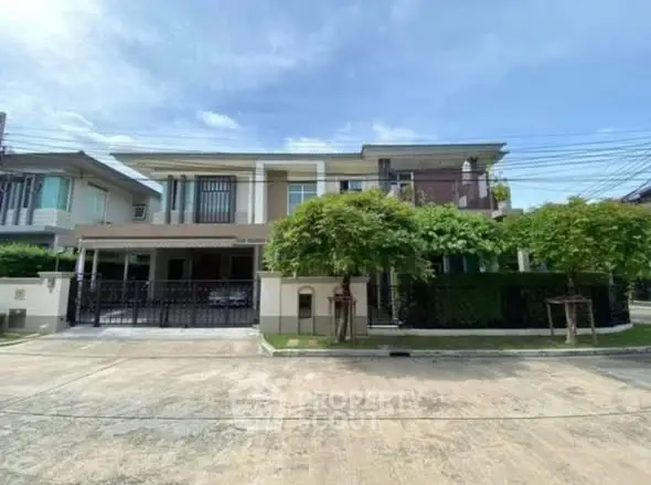 Modern two-story house with lush greenery and spacious driveway in a serene neighborhood.