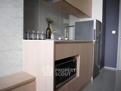 Modern compact kitchen with sleek cabinetry and stainless steel appliances in a stylish apartment.