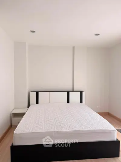 Modern minimalist bedroom with sleek black and white bed frame and cozy ambiance.
