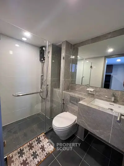 Modern bathroom with sleek design, featuring glass shower enclosure and stylish fixtures.