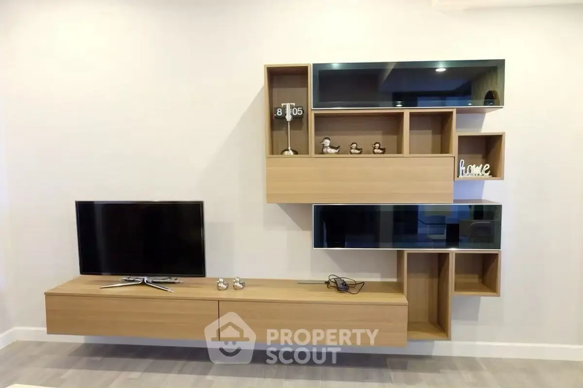 Modern living room with stylish wall-mounted TV unit and decorative shelves.