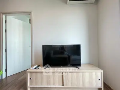Modern living room with sleek TV on wooden cabinet, showcasing minimalist design and natural light.