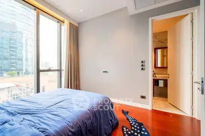 Modern bedroom with ensuite bathroom and large window offering city views.