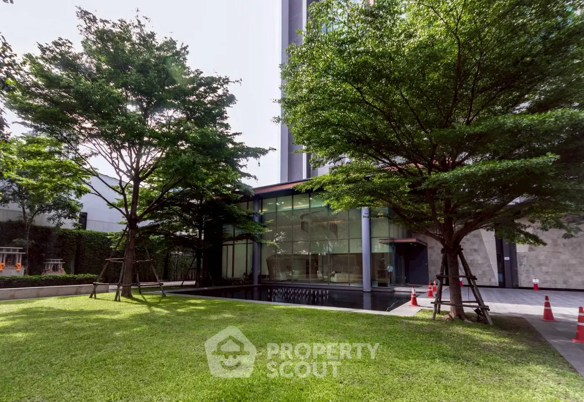 Modern building exterior with lush green garden and glass facade, ideal for urban living.