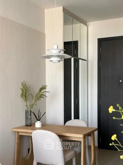 Stylish modern dining area with wooden table and elegant pendant light in a cozy apartment.