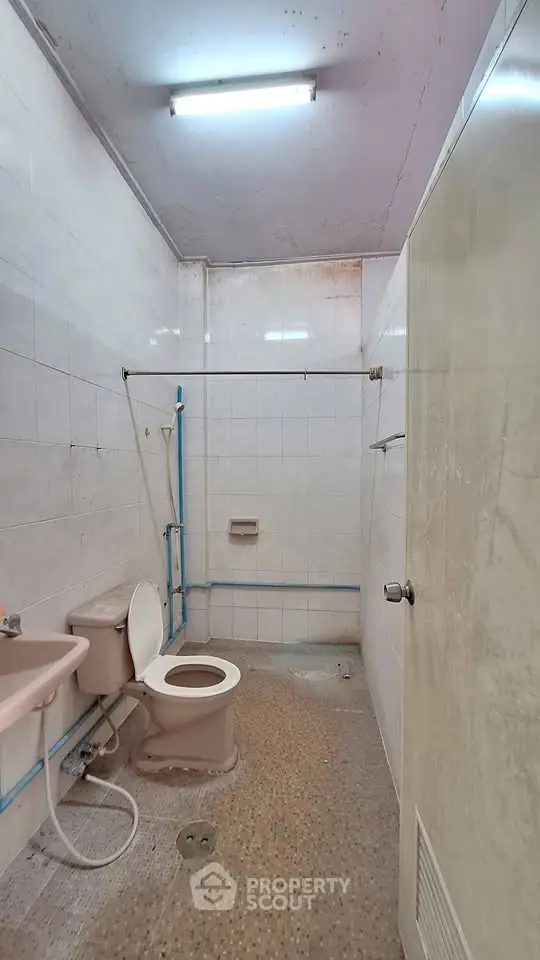 Modest bathroom with basic fixtures and tiled walls, ideal for renovation.