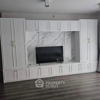 Modern living room with elegant built-in white cabinetry and sleek marble backdrop.