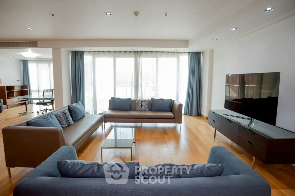 Spacious modern living room with elegant sofas and large TV, perfect for relaxation and entertainment.