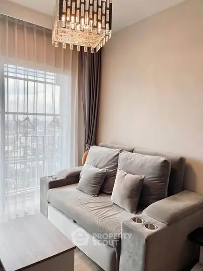 Cozy living room with plush gray sofa and elegant chandelier, perfect for relaxation.