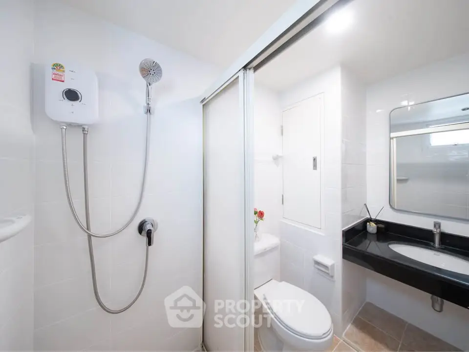 Modern bathroom with sleek design, featuring a shower, toilet, and stylish vanity in a bright setting.