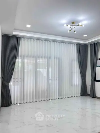 Spacious modern living room with elegant curtains and sleek lighting fixture.
