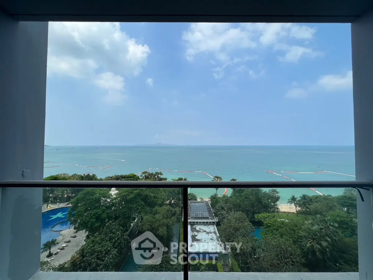 Stunning ocean view from a high-rise balcony overlooking lush greenery and a pool.