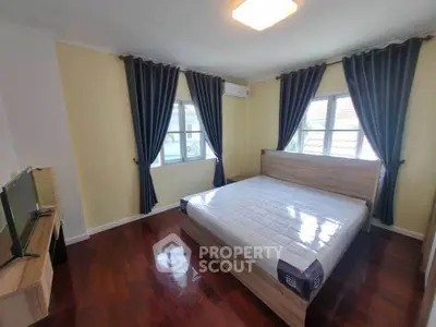 Spacious bedroom with hardwood floors and large windows in a modern home.