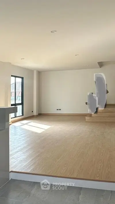 Spacious open-plan living room with natural light and modern flooring