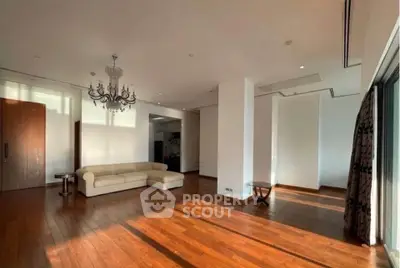 Spacious living room with elegant chandelier and hardwood floors in luxury apartment