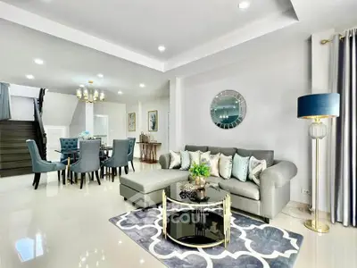 Elegant living room with modern decor and open dining area, featuring stylish furniture and chic lighting.