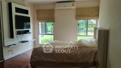 Spacious bedroom with large windows overlooking a lush green view, featuring modern amenities.